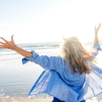 Melanie Liedle-Frau breitet die Arme am Strand aus Melanie Liedle-Frau breitet die Arme am Strand aus